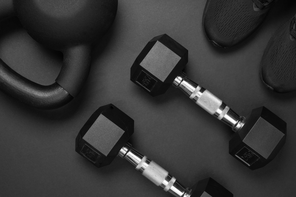 Pair of black hex dumbbells placed on a gym floor with fitness equipment.