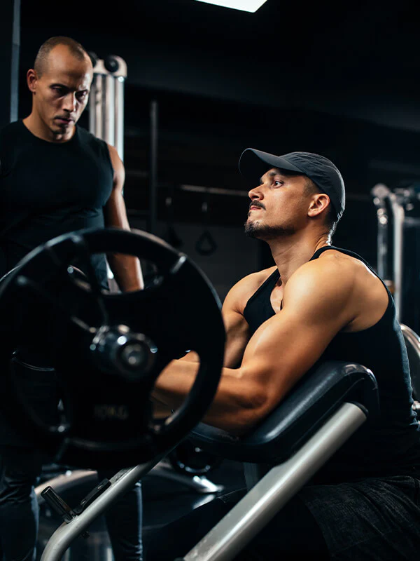 Personal trainer guiding a man during a strength training workout in the gym.