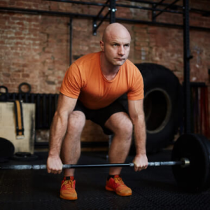 Athlete preparing to perform a barbell deadlift in a modern gym.