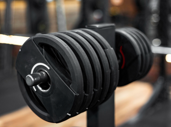 Close-up of adjustable weight plates mounted on a barbell in a gym.